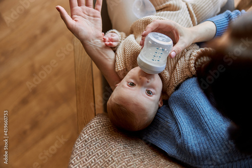 Mother feeding newborn baby from bottle with milk