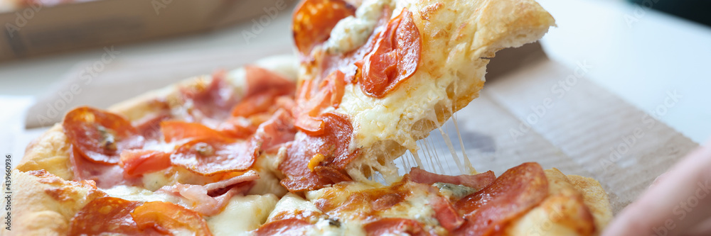 Man taking piece of pizza with sausage and cheese in his hand closeup Man taking piece of pizza with sausage and cheese in his hand closeup