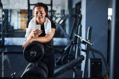 Smiling beautiful woman with cell phone in gym