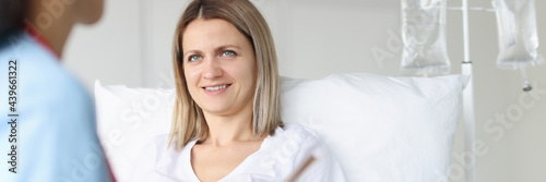 Doctor examining woman lying on bed in hospital