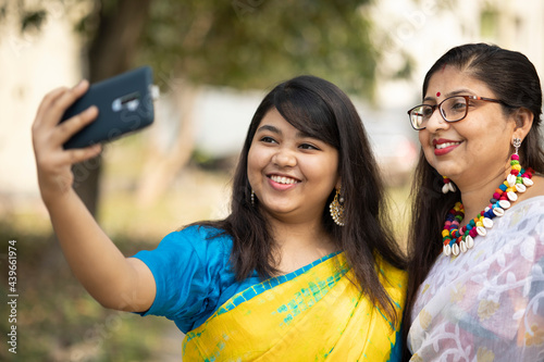 Indian woman taking selfie with smartphone at outdoors and wearing Indian traditional Sari
