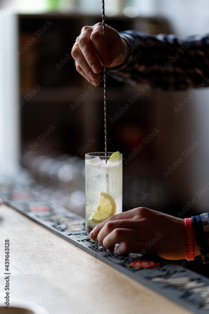 Bartender is stirring and mixing cocktail in a restaurant, no face, hands only visible