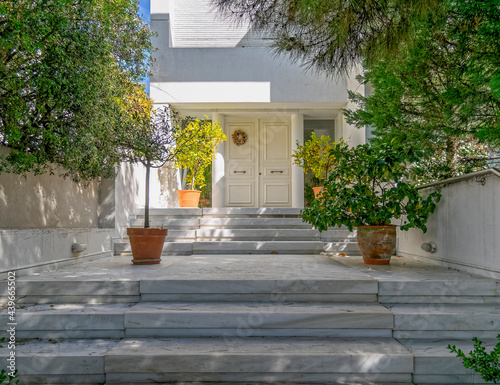 elegant white house facade and entrance door with potted plants