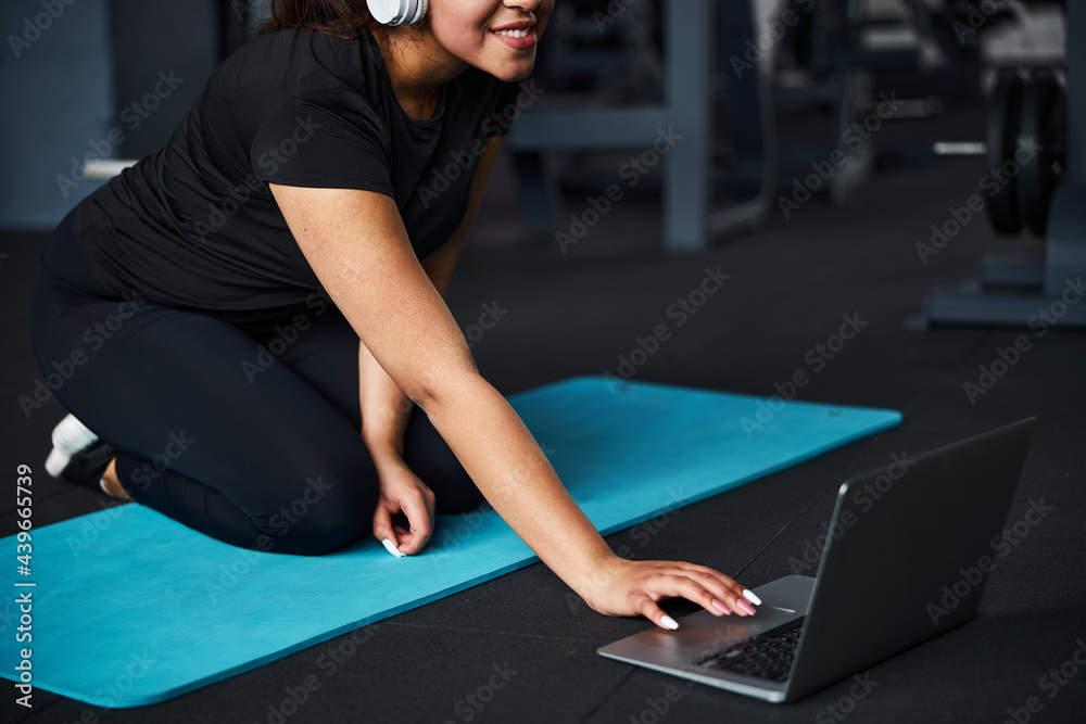 Serene female exercising in gym online with gadgets