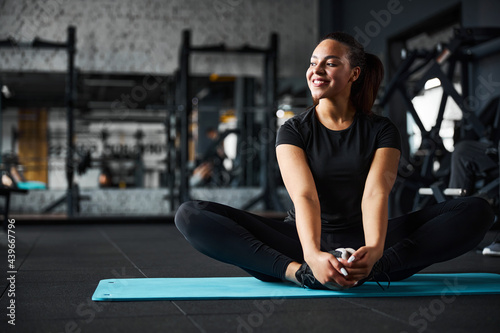 Serene pretty female doing mobility exercises in gym