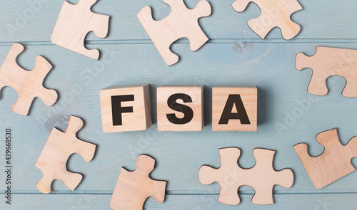 Blank puzzles and wooden cubes with the FSA Flexible Spending Account lie on a light blue background.