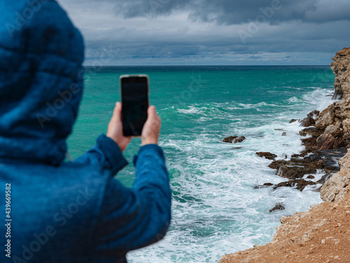 A woman take a photo of the sea on smartphone