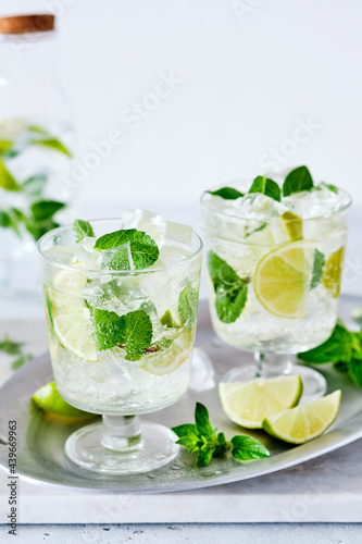 Cold refreshing summer lemonade mojito in a glass on a grey concrete or stone background. Copy space.