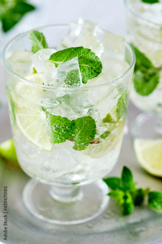 Cold refreshing summer lemonade mojito in a glass on a grey concrete or stone background. Copy space. Cold refreshing summer lemonade mojito in a glass on a grey concrete or stone background. Copy space.