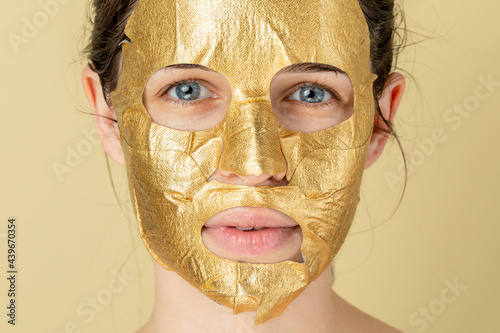 Studio portrait of a woman with a golden face mask  photo