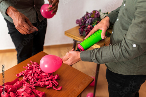 Ethnic gay couple inflating clored balloons photo