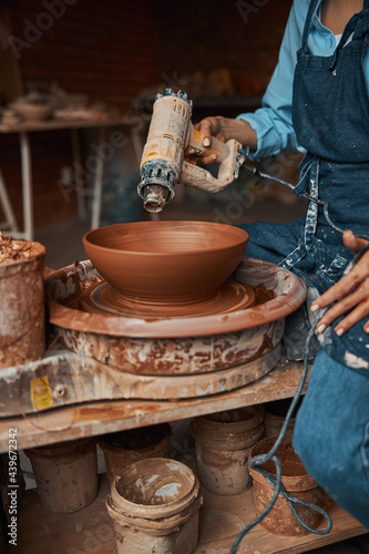 Female artisan wearing apron making clay bowl in art modern studio