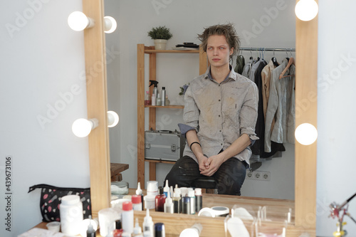 Young man with zombie greesepaint sitting in front of mirror in studio photo