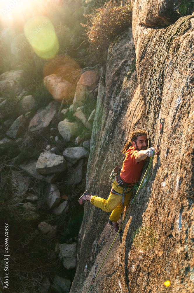 Alpinist climbing high rock during training at sunset Alpinist climbing high rock during training at sunset