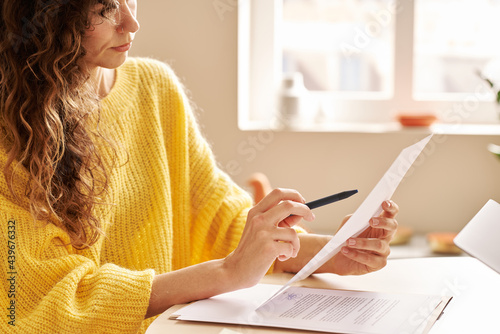 Attentive young woman reading contract in workplace photo