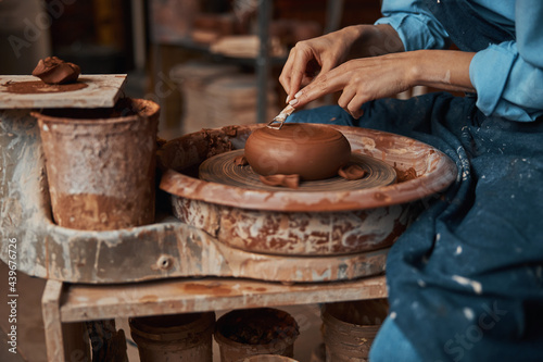 Unrecognized craft woman sitting near the pottery wheel in art boutique
