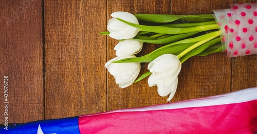 American flag and white tulip flowers on wooden background