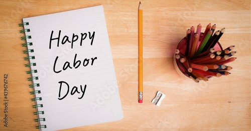 Happy labor day text on dairy and pencil stand on wooden surface