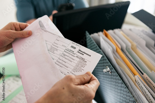 Taxes: Woman Opens Envelope With 1099 Miscellaneous Income Form photo