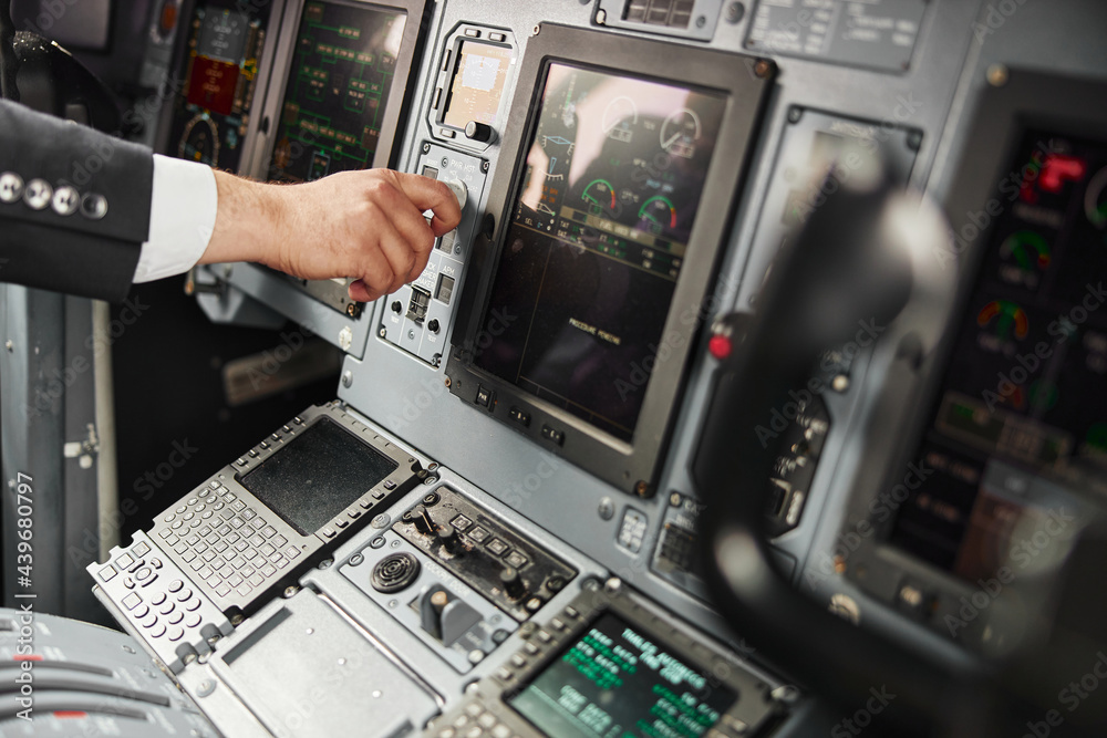 Male pilot turn button on passenger airplane jet