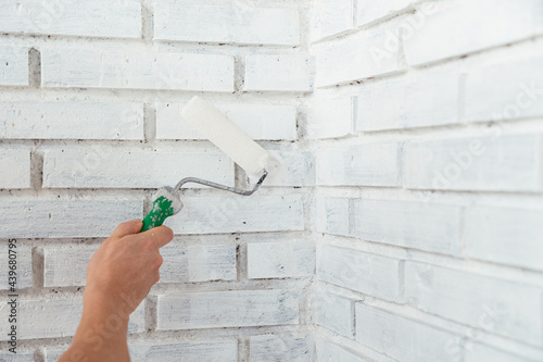 Man with roller painting brick wall photo