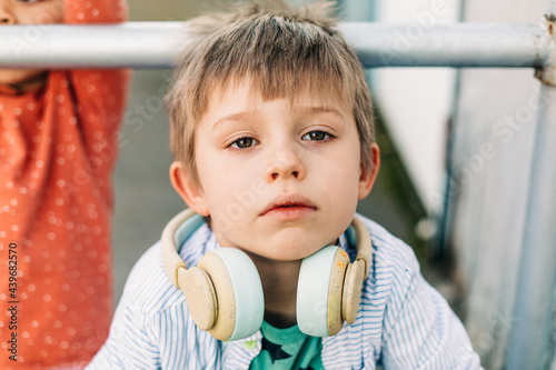 little boy with headphones sitting by a metal bar photo