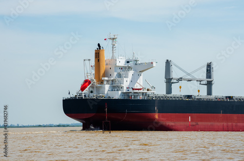 close up on a red and black cargo ship sailing on the water