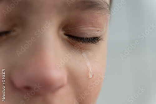 Tear rolls down the boy's cheek, his eyes are closed, he is upset and crying. Sad, unhappy emotions of child.