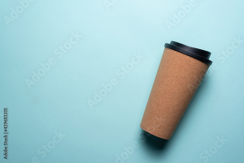 Coffee cork mug with a cover on a blue flat lay background.