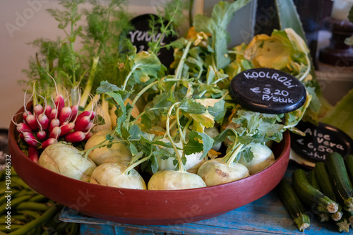 A variety of fresh vegetables displayed in a bowl with radishes and kohlrabi