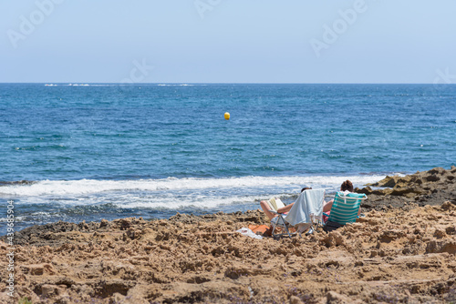 Rocky beach where two people sunbathe in hammocks, Javea, Alicante, Spainn photo