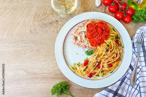 Italian Traditional Dish"Tagliolini alla granseola",spaghetti with spider crabs,cherry tomatoes,olive oil,white wine,parsley,garlics,salt and peppers on plate with wooden table background.Top view