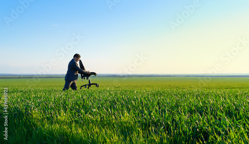 businessman carries an office chair in a field to work, freelance and business concept, green grass and blue sky as background