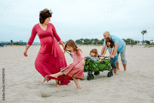 Pregnant mom pulling wagon across beach photo