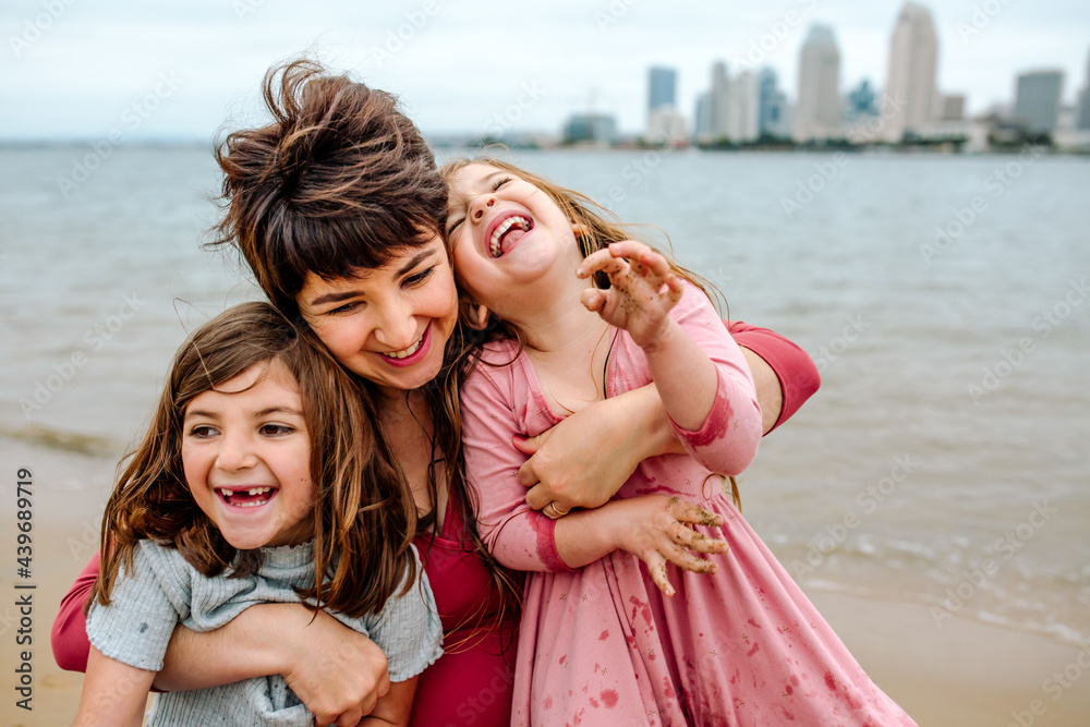 Mother and daughters laughing at the beach Mother and daughters laughing at the beach