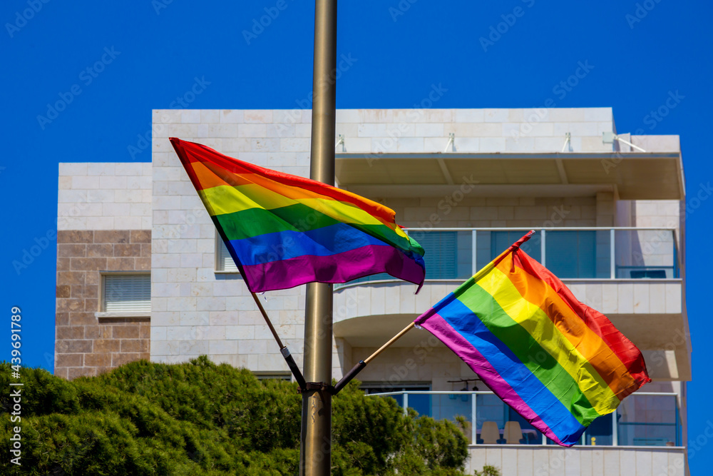 Rainbow flags hanging on a pole and waving on the air with blue sky background. LGBTQ community. Flags - Six-stripes version