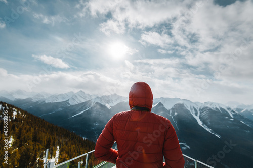 A man with a red jacket looking at the Canadian Rockie mountains in Banff, Canada
