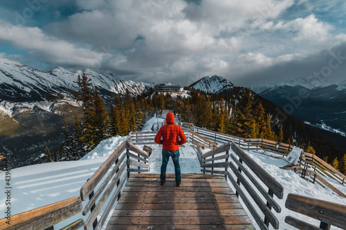 A man with a red jacket looking at the Canadian Rockie mountains in Banff, Canada