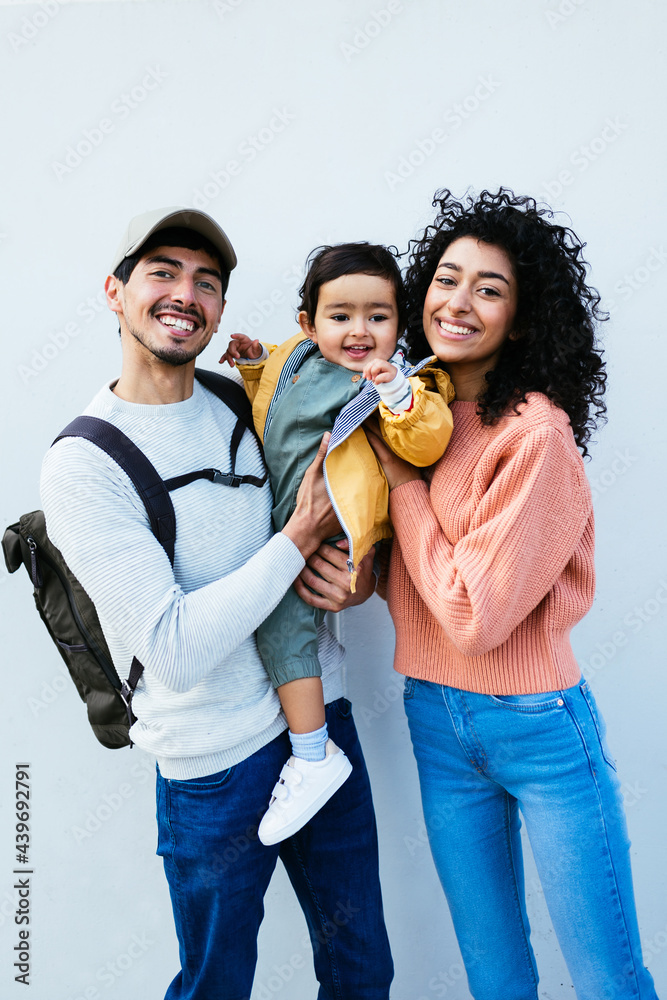 Happy Indian parents with baby against gray wall Stock Photo | Adobe Stock