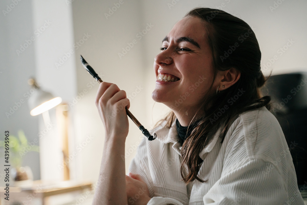 Portrait of happy Young woman writing japanese kanji characters with a brush and ink Portrait of happy Young woman writing japanese kanji characters with a brush and ink