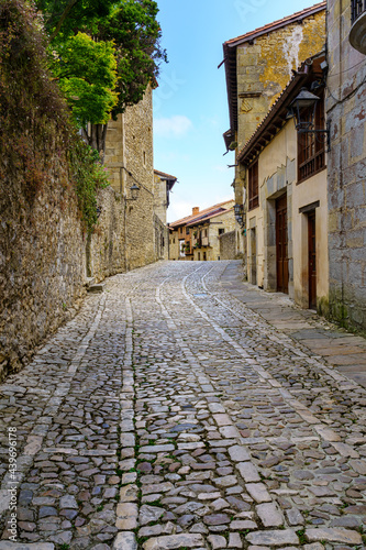 Narrow steep street with old houses and old stone pavement. Santillana del Mar.