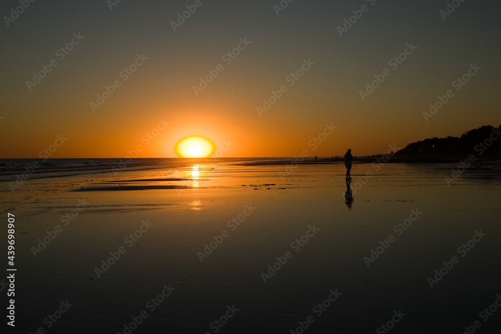 sunset on a beach with silhouettes of people backlit