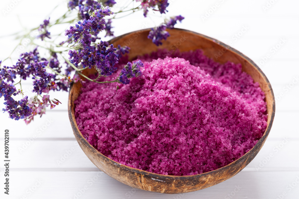 Sea salt in bowl, aroma oil in bottles, Wellness and flowers on grey textured background and flowers on vintage wooden background. Selective focus.