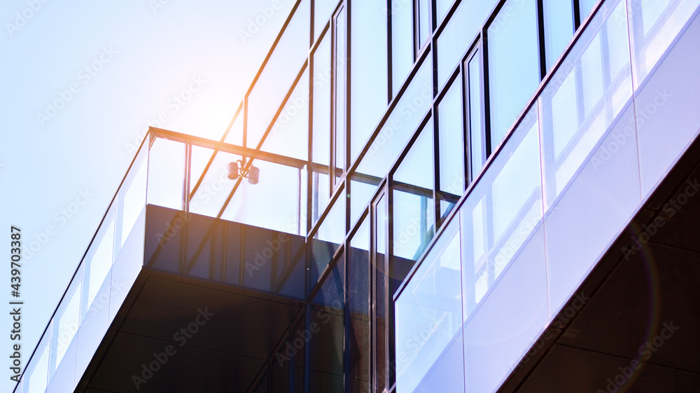 Fototapeta premium Reflection of modern commercial building on glass with sunlight. Geometric structure glass windows. 