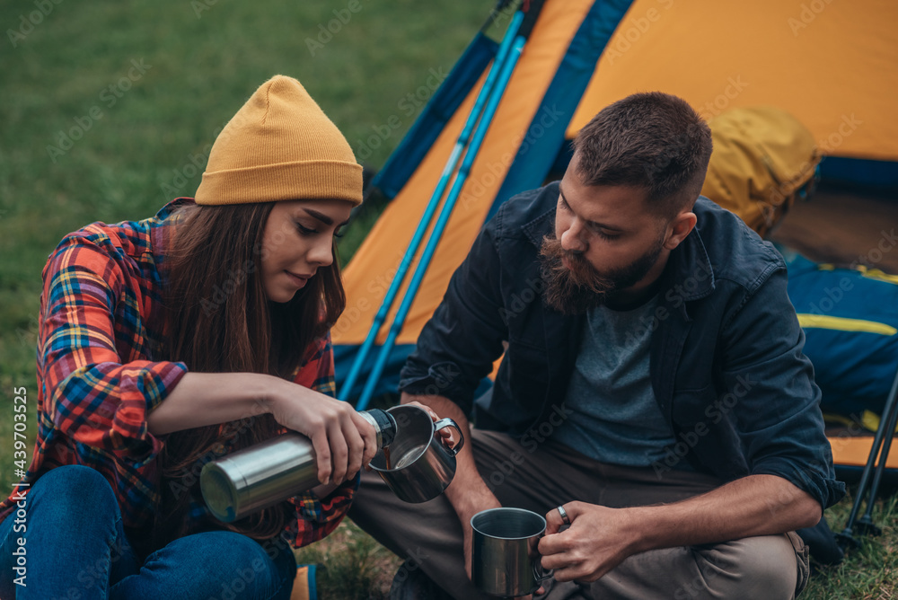 Couple of campers camping in the nature and drinking coffee from metal cups