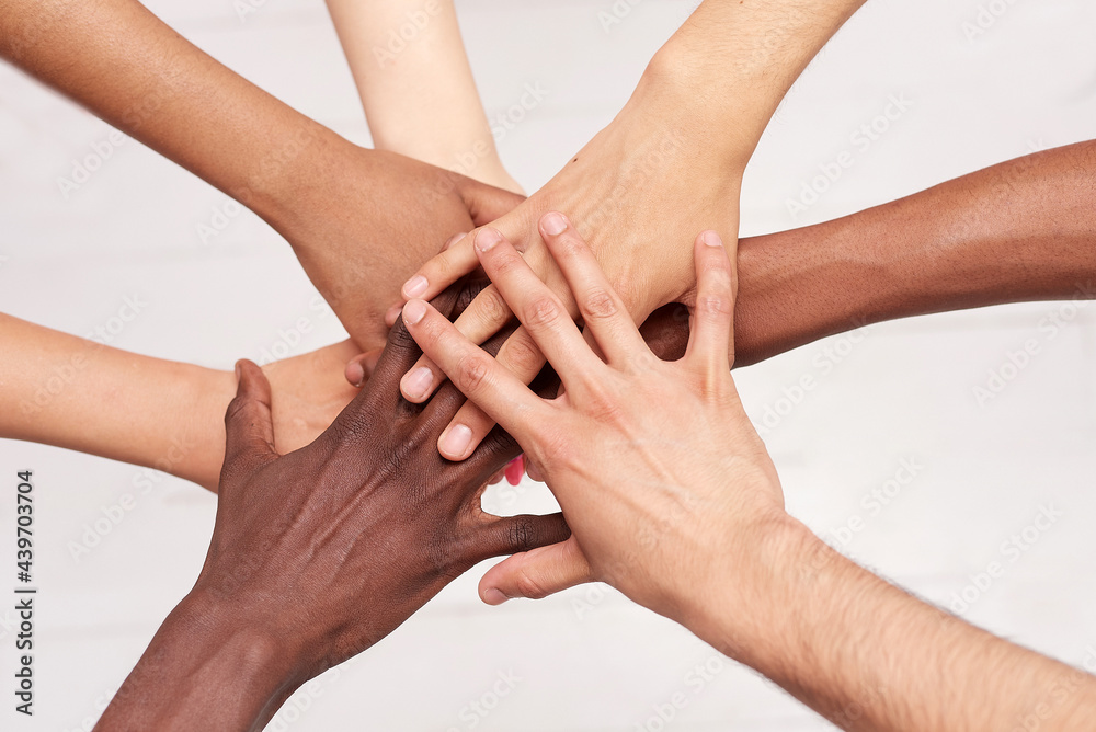 Fototapeta premium Young people fold their hands. Multinational friends with a stack of hands demonstrating unity and teamwork