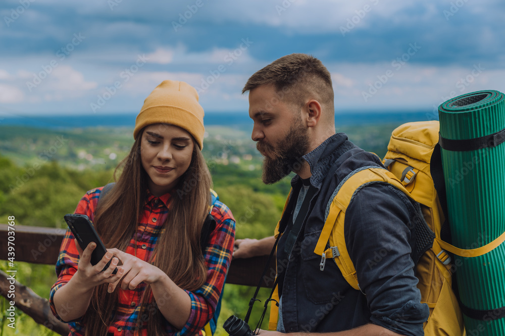 Young couple of hikers using smartphone while trying to find out their location