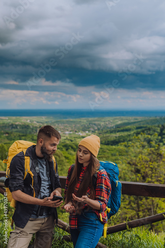 Young couple of hikers using smartphone for orientation in the nature