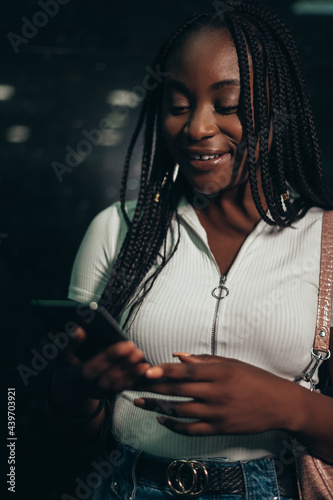 Happy african american woman using smartphone while in the subway