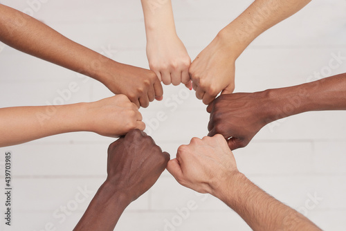 Multiethnic people holding hands in a circle together, multiethnic business team promising help and support, close-up, top view